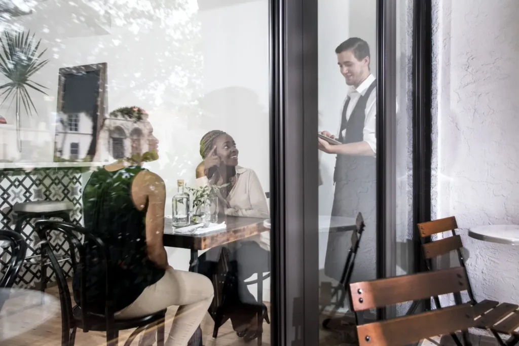 Switchable Glass Redefines Privacy Expectations: But How? Restaurant space with smart glass windows providing privacy control, natural light management, and enhanced guest comfort.