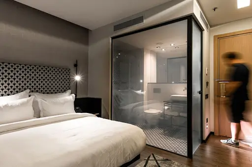 The Smart Glass Revolution: Why UAE is Making the Switch Luxury hotel room featuring switchable smart glass bathroom partition for instant privacy control, modern interior design, and enhanced guest comfort.