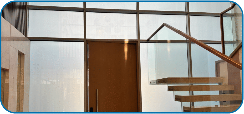 A luxury hotel room in Dubai with a switchable smart glass partition separating the bathroom, shown in its opaque state for privacy.
